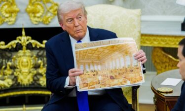 US President Donald Trump holds a rendering of the planned White House Ballroom extension during a meeting in the Oval Office on Wednesday.