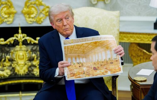 US President Donald Trump holds a rendering of the planned White House Ballroom extension during a meeting in the Oval Office on Wednesday.