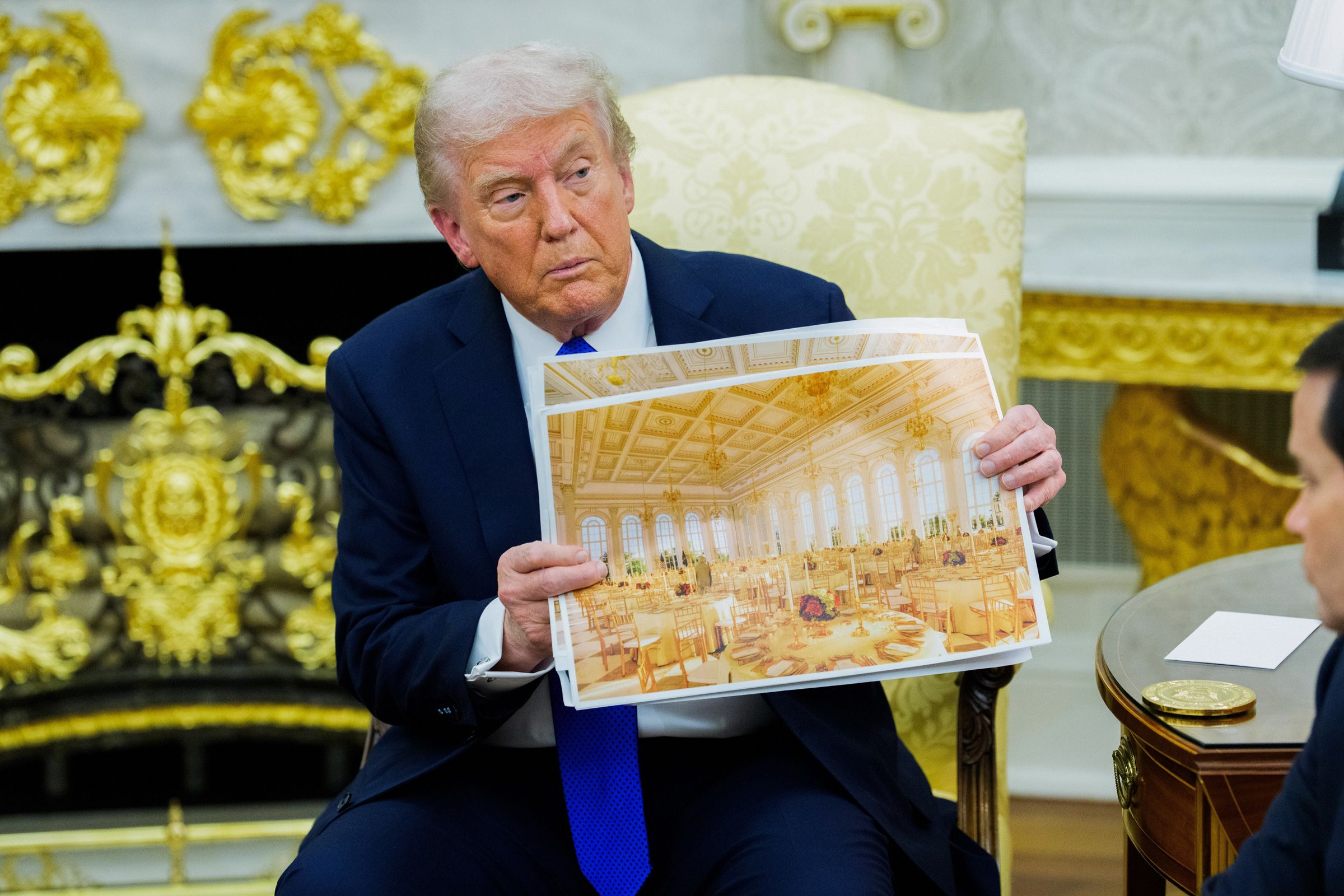 US President Donald Trump holds a rendering of the planned White House Ballroom extension during a meeting in the Oval Office on Wednesday.
