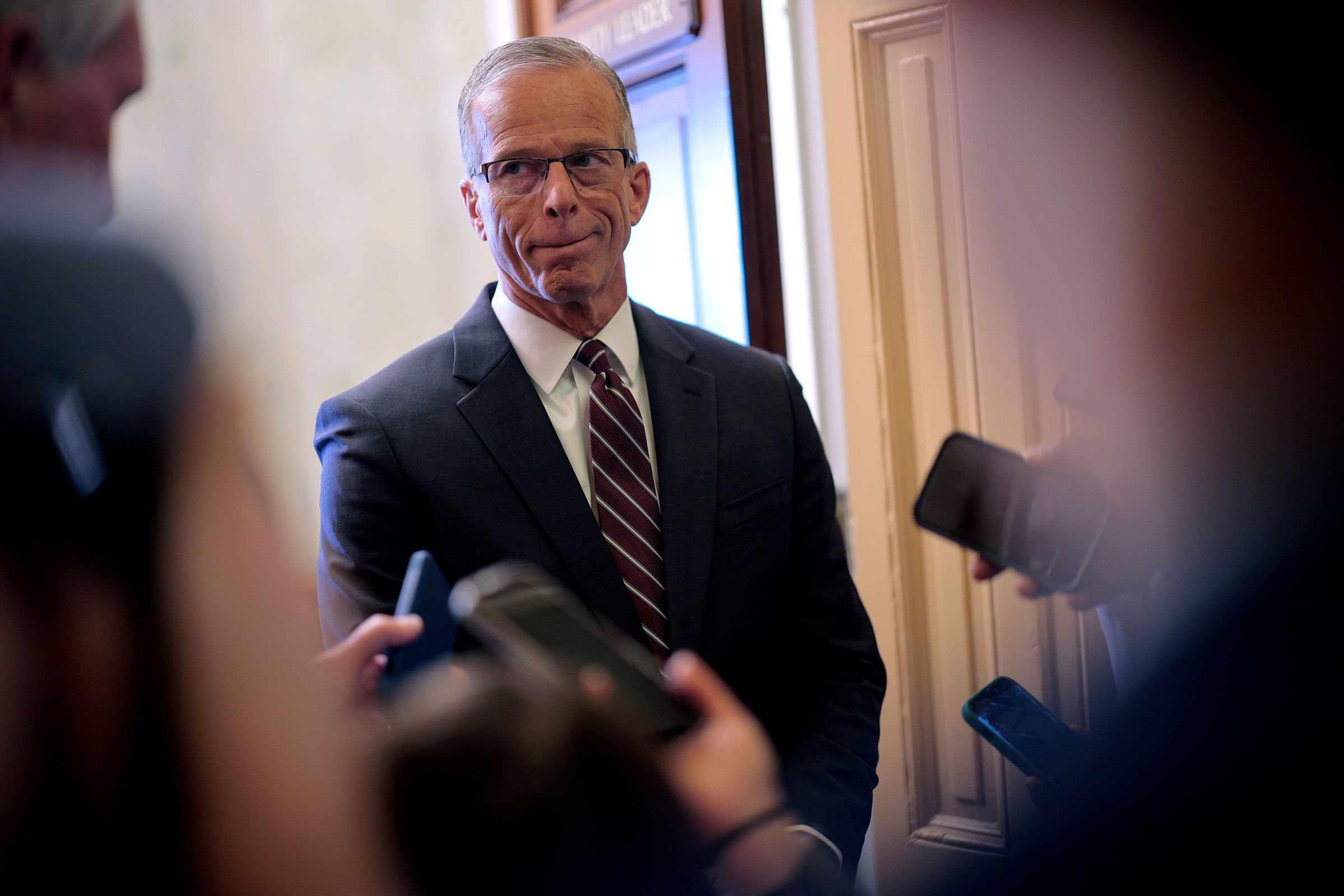 Senate Majority Leader John Thune talks to reporters while standing in the doorway of his office at the US Capitol on Wednesday