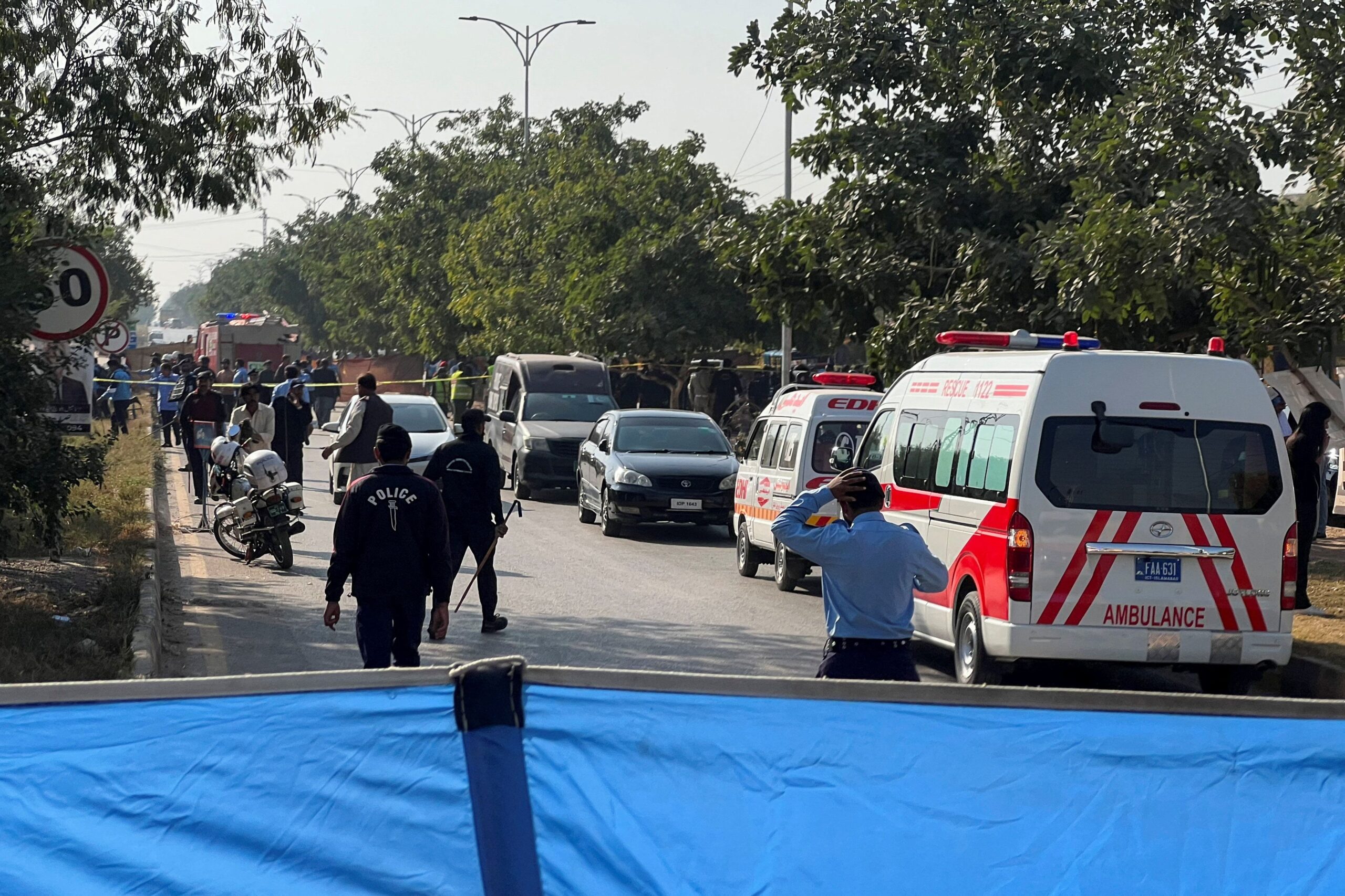 Police officers and ambulances attend the scene after a blast outside a court building in Islamabad