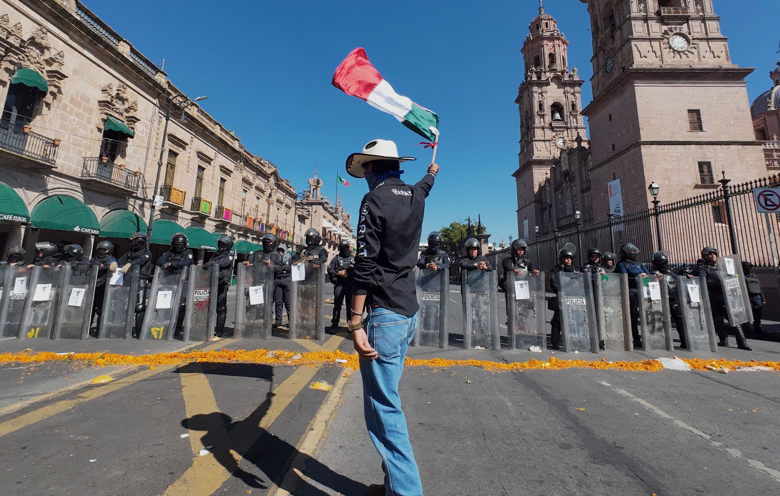 <i>Jordi Lebrija/AFP/Getty Images via CNN Newsource</i><br/>A protester waves a Mexican flag in front of police officers during a demonstration against the assassination of Uruapan's mayor at the Government Palace in Morelia