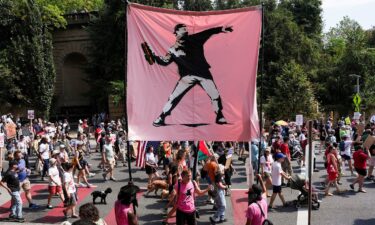 Demonstrators hold a banner in the style of the artist Banksy