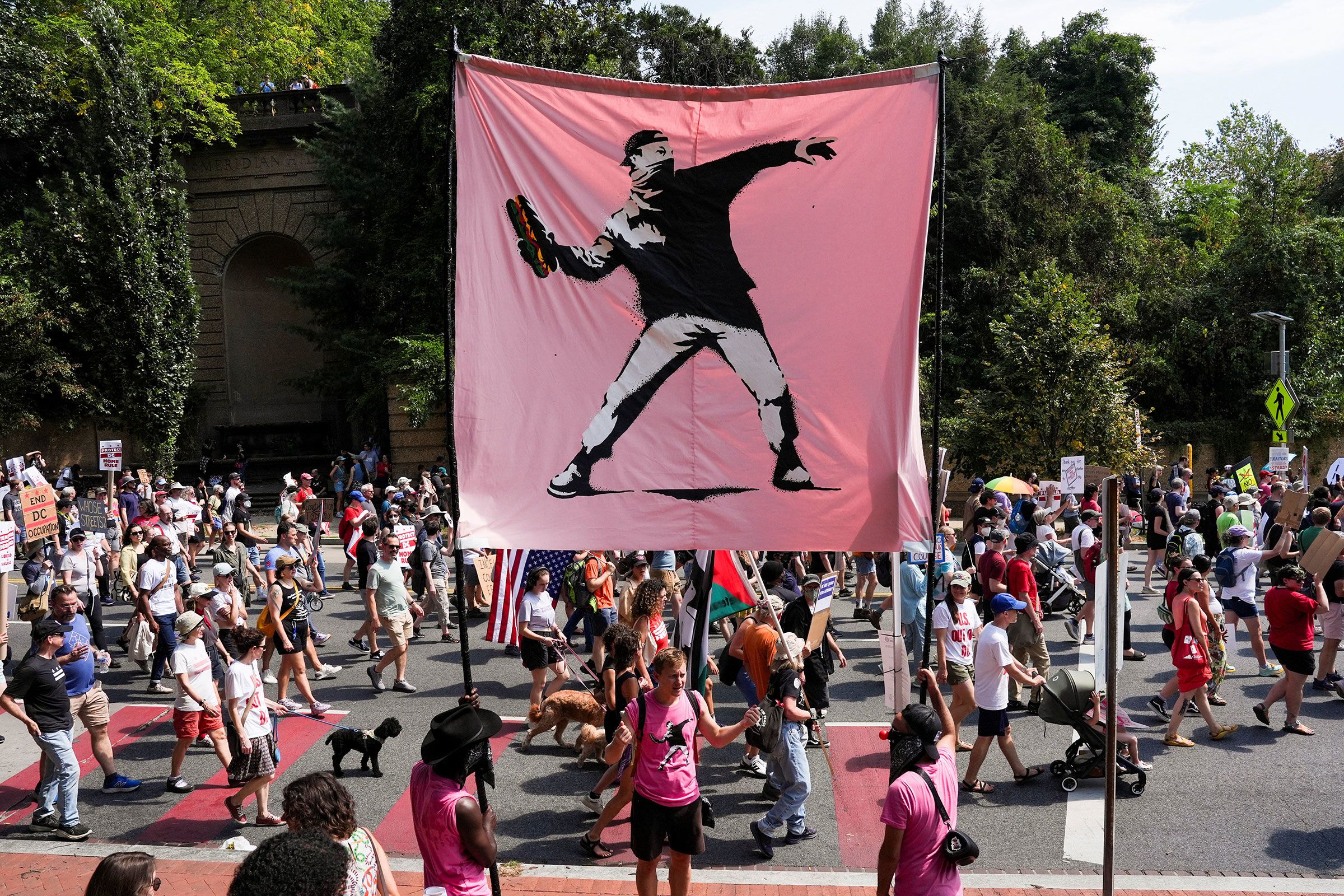 Demonstrators hold a banner in the style of the artist Banksy