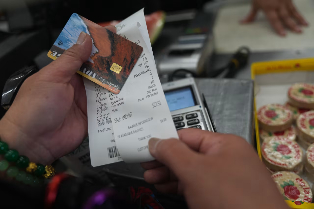 A woman checks her balance left after purchasing food supplies with a California EBT card in Los Angeles, on Friday.