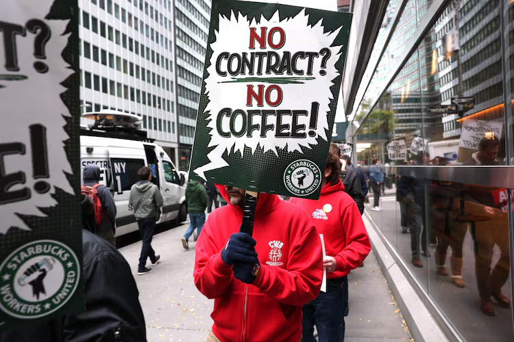 In this Oct. 28, 2025, file photo, Starbucks baristas gather outside a Starbucks store as they protest against the company during a rally to demand a new contract in New York.