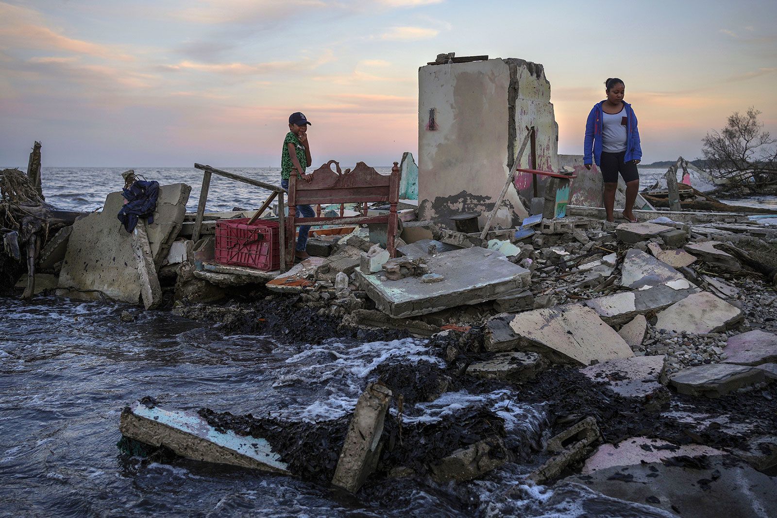 <i>Felix Marquez/AP/File via CNN Newsource</i><br/>Researchers say individuals will often bear the economic burden of climate change. Yahir Mayoral and Emily Camacho walk amid the rubble of their grandmother's home