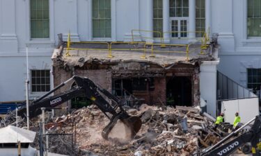 An excavator works to clear rubble after the demolition of the East Wing of the White House