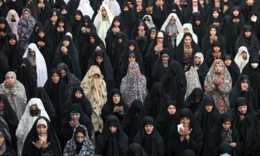 People walk past a display sign at a currency exchange bureau as the value of the Iranian rial drops