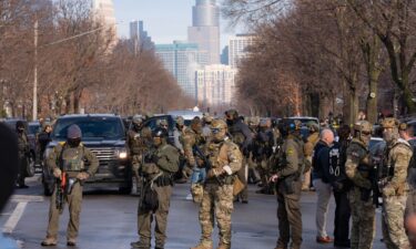 Federal agents including ICE and US Border Patrol stand with weapons along Portland Ave. near the scene where federal agents shot and killed a woman earlier in Minneapolis