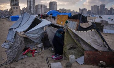 Iman Al-Atoutt repairs her tent after days of rain in a makeshift camp for displaced Palestinians set up on the beach in Gaza City