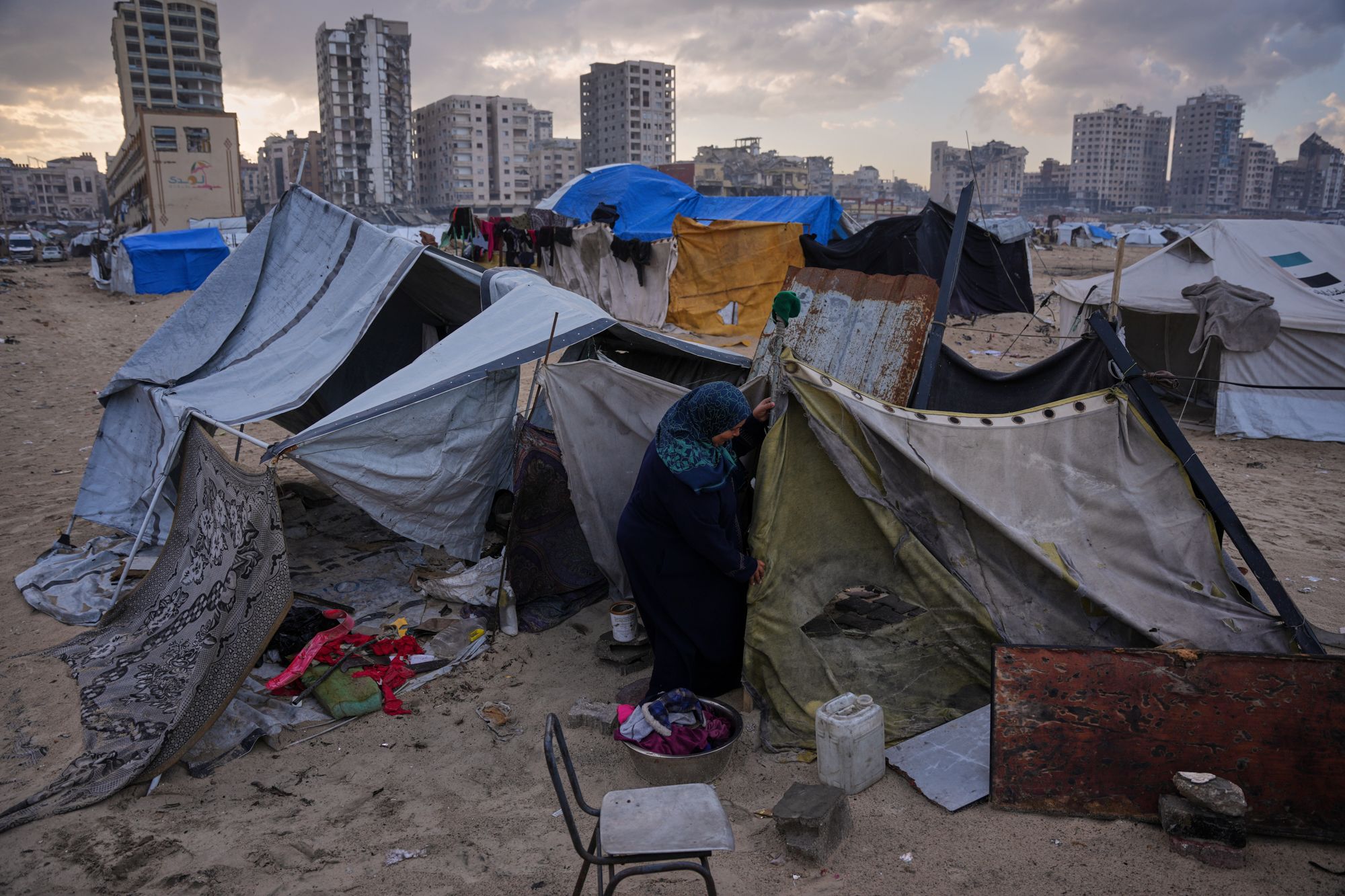 <i>Abdel Kareem Hana/AP via CNN Newsource</i><br/>Iman Al-Atoutt repairs her tent after days of rain in a makeshift camp for displaced Palestinians set up on the beach in Gaza City