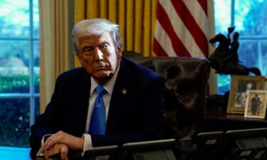 President Donald Trump looks on as he holds a pen in the Oval Office at the White House in Washington