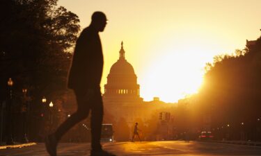 Pedestrians walks along Pennsylvania Avenue near the U.S. Capitol during sunrise on November 5