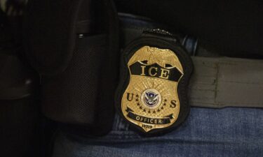A federal agent wears a badge of Immigration and Customs Enforcement while standing outside an immigration courtroom at the Jacob K. Javits Federal Building in New York