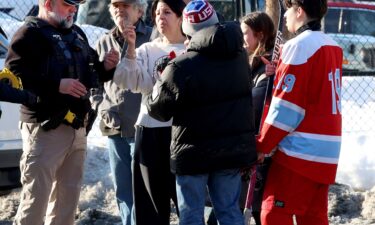 Hockey parents and a player speak to a police officer outside of the Lynch Arena in Pawtucket