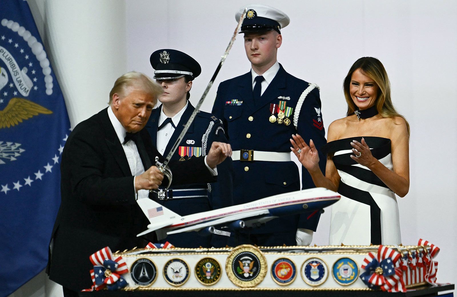 Donald Trump uses a saber to cut into a cake topped with a model of a new Air Force One design during the Commander-In-Chief inaugural ball on January 20.