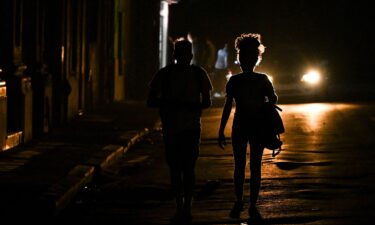 People walk down a dark street during a blackout in Havana on March 4