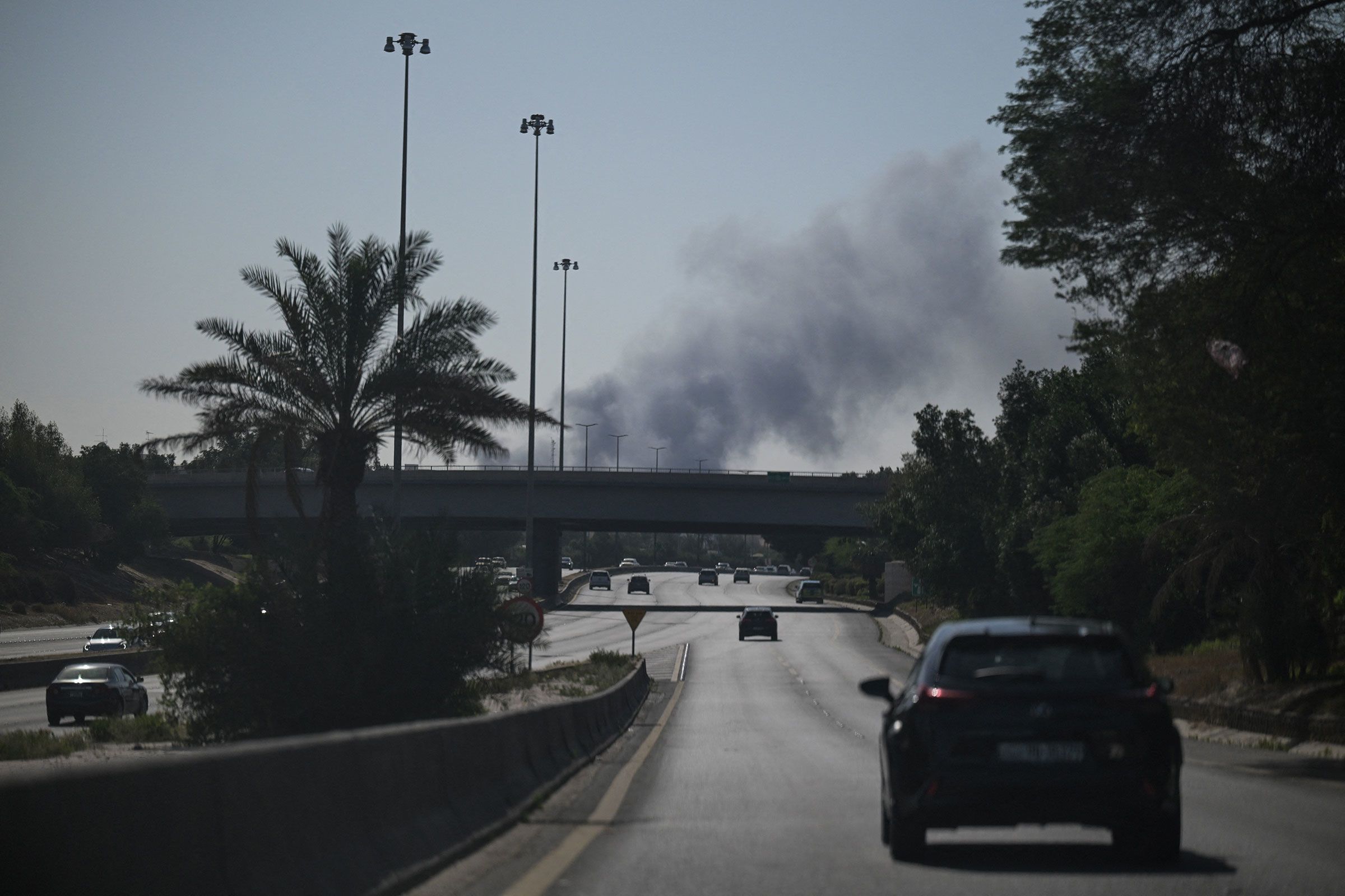<i>AFP/Getty Images via CNN Newsource</i><br/>Motorists drive along a street as smoke rises from a reported Iranian strike in the area where the US Embassy is located in Kuwait City on March 2.