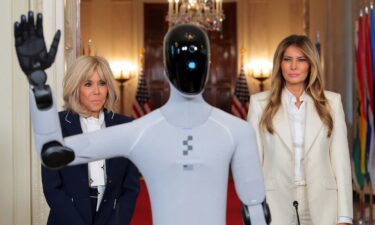 US first lady Melania Trump and French first lady Brigitte Macron look at a humanoid robot