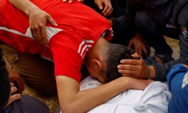 A mourner leans over the body of Majdi Aslan at Al-Aqsa Martyrs Hospital in Deir al-Balah