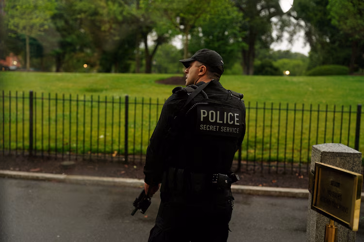 A member of the U.S. Secret Service watches holding his weapon after alleged gunfire was heard nearby, at the White House in Washington, D.C., U.S., May 23, 2026.