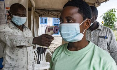 A border health officer at the Busunga crossing between Uganda and the Democratic Republic of Congo checks a traveler's temperature in Bundibugyo