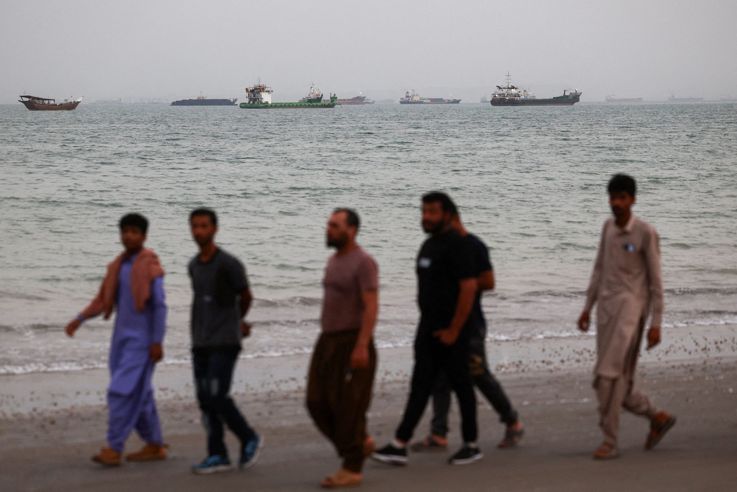**This image is for use with this specific article only**
People walk on a beach with the Strait of Hormuz visible in the background, near Bandar Abbas, Iran, on Friday.
