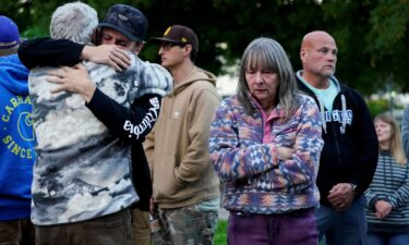 People embrace as they attend a vigil after a chemical tank rupture at the Nippon Dynawave Packaging pulp and paper mill