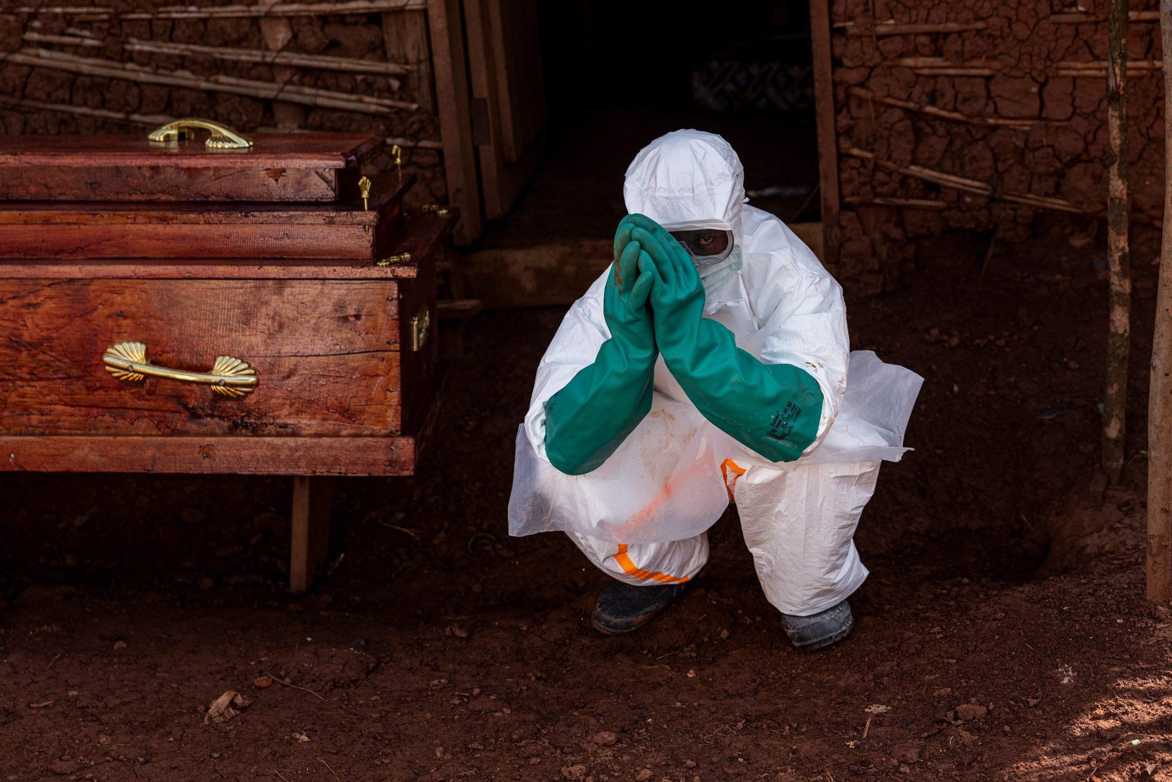 <i>Michel Lunanga/Getty Images via CNN Newsource</i><br/>A health worker wearing protective equipment crouches beside the coffin of a suspected Ebola victim during safe burial procedures outside a family home in the community of Mongbwaluon on May 24
