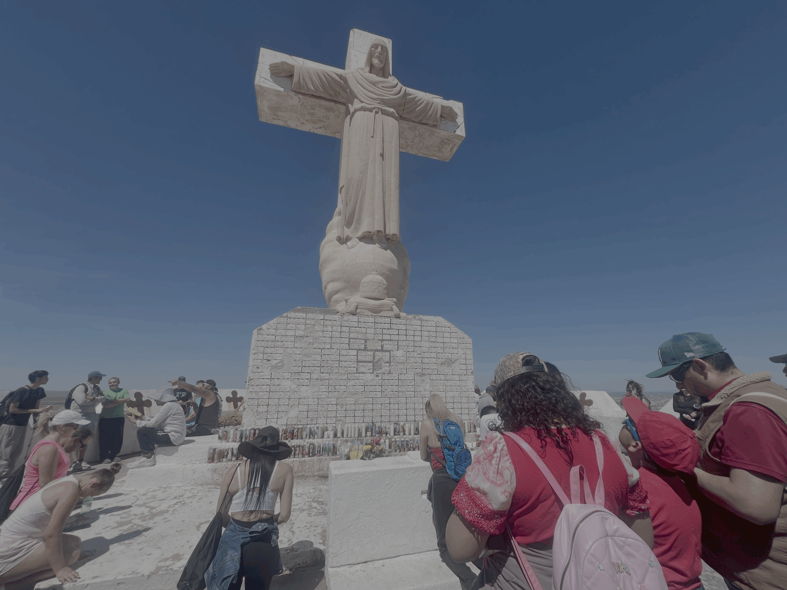 On Good Friday, April 3, 2026, the faithful pray at the foot of white sculpture of Jesus Christ after making a Good Friday pilgrimage to the top of Mount Cristo Rey in Sunland Park, New Mexico.