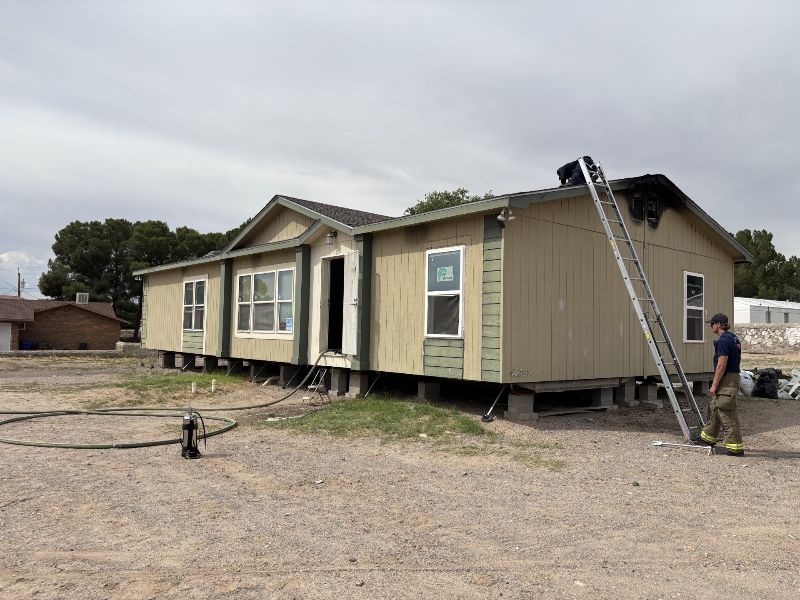 A Las Cruces firefighter at the perimeter of a mobile home on Calle Sosa after extinguishing a fire in the attic.