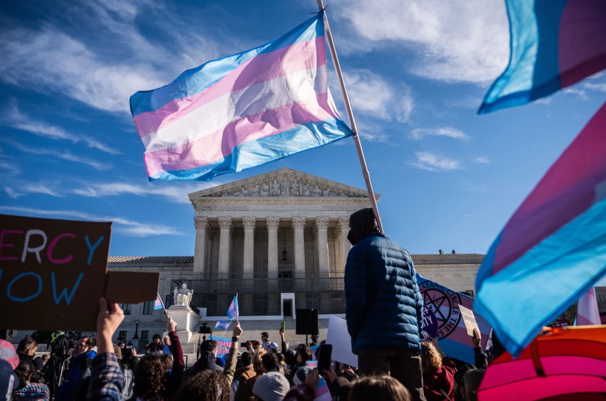 <i>Julia Demaree Nikhinson/AP via CNN Newsource</i><br/>Protesters wave transgender pride flags outside the Supreme Court as it hears arguments over state laws barring transgender girls and women from playing on school athletic teams in January in Washington