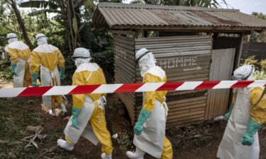 MSF teams wearing full protective equipment reinforce perimeter barriers around a restricted Ebola isolation zone and basic hygiene facilities
