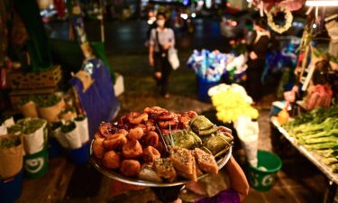 A food vendor carries a tray full of delicacies along an alley at Pak Khlong Talat market in Bangkok.