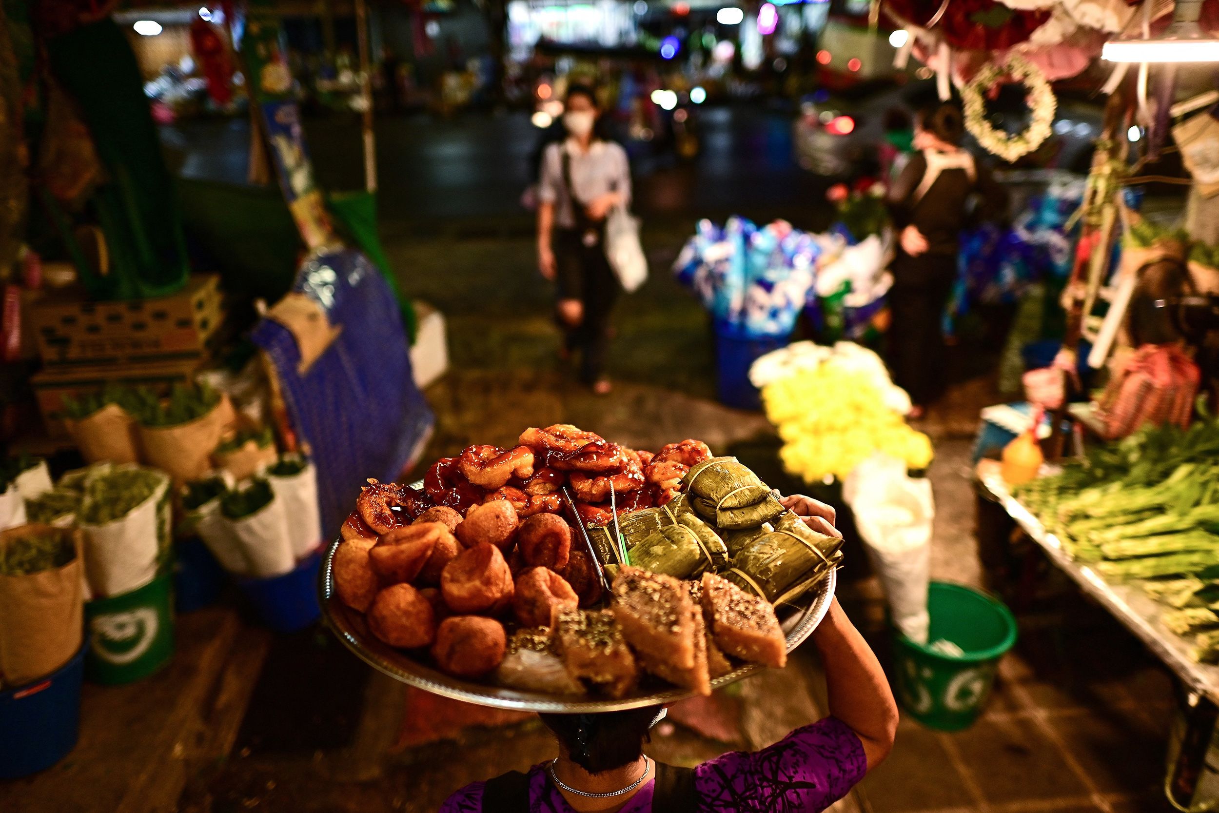 <i>Manan Vatsyayana/AFP/Getty Images via CNN Newsource</i><br/>A food vendor carries a tray full of delicacies along an alley at Pak Khlong Talat market in Bangkok.