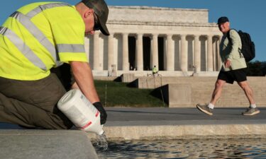 A US National Park Service worker dumps bottles of hydrogen peroxide in the Lincoln Memorial Reflecting Pool as part of their effort to mitigate an algae bloom which followed the completion of recent renovations in Washington
