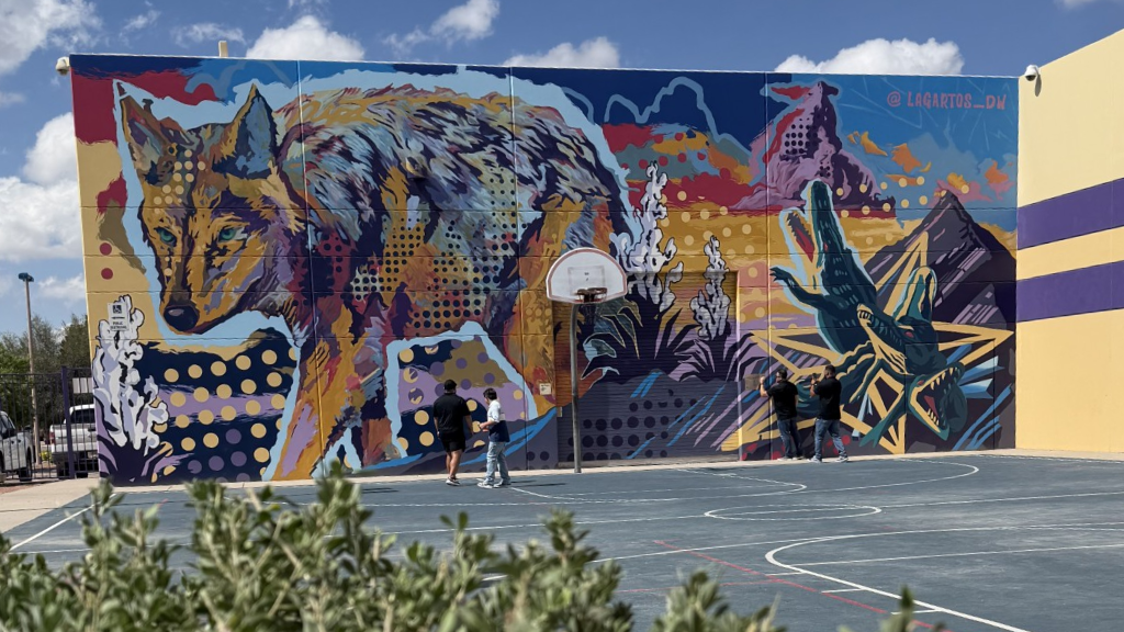 A vibrant mural featuring a wolf and a dinosaur on a basketball court