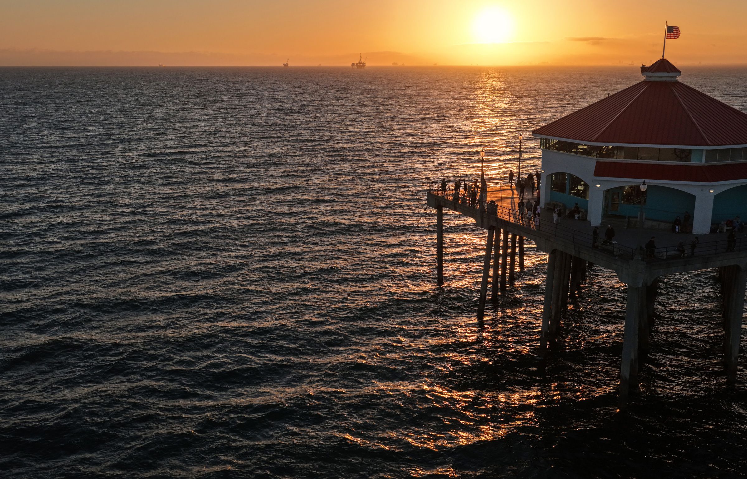 <i>Mario Tama/Getty Images via CNN Newsource</i><br/>The sun sets over the Pacific Ocean as people gather on Huntington Beach Pier on July 1