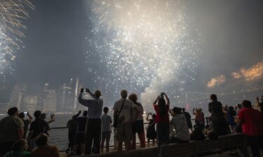 People watch as fireworks light up the Manhattan skyline during the Macy's Fourth of July Fireworks celebration on the East River at Brooklyn Bridge Park on July 4 in New York.