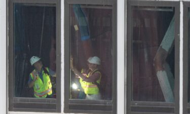 People inspect a buckled support beam inside 235 East 42nd Street