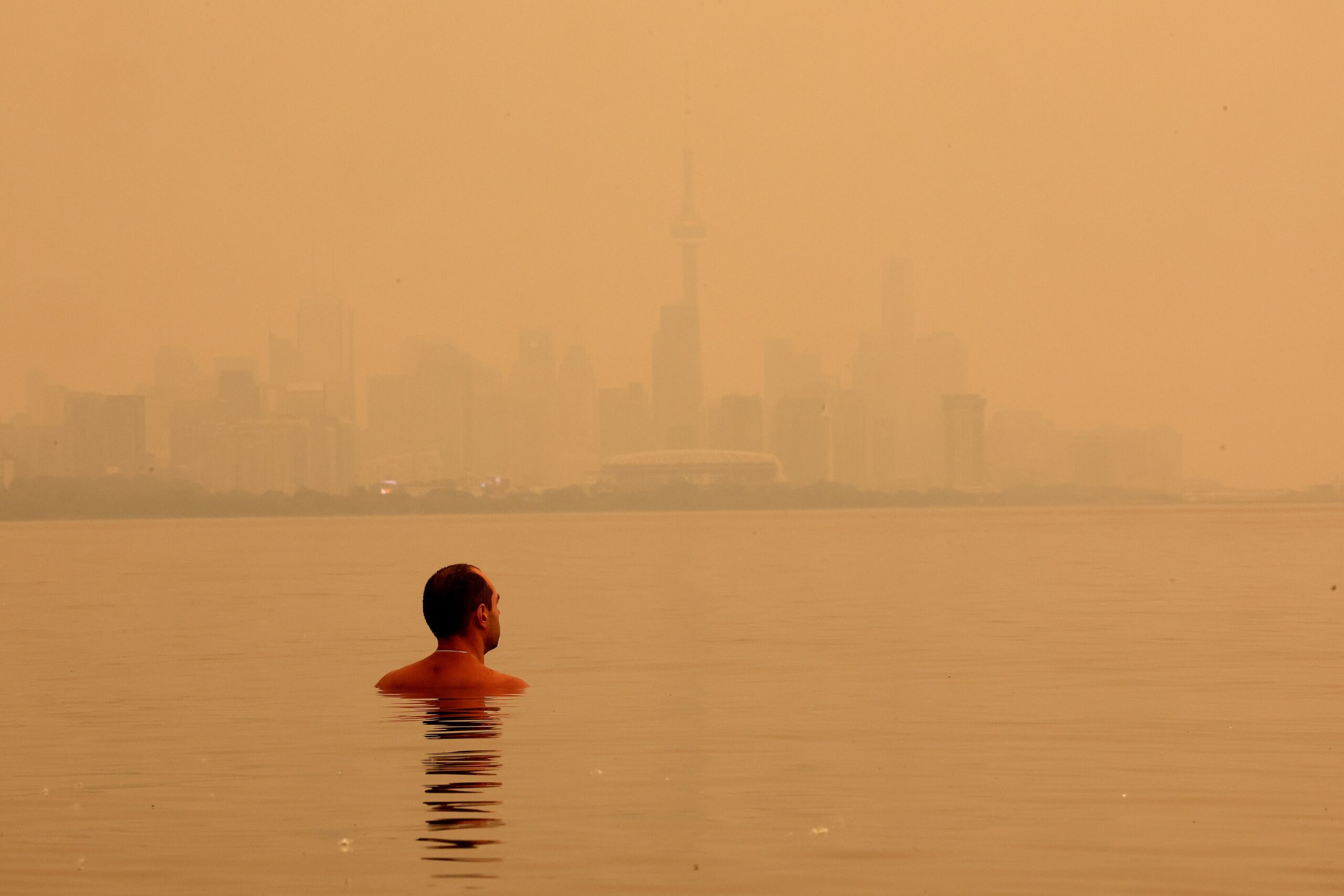 <i>Steve Russell/Toronto Star/Getty Images via CNN Newsource</i><br/>A swimmer checks out the view of the smoke from Northern Ontario forest fires that has the City of Toronto skyline shrouded in haze as viewed from Humber Park West in Toronto