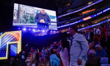 People watch as U.S. Sen. John Fetterman (D-PA) appears on a video on the first day of the 2026 Republican National Convention at the American Airlines Center in Dallas