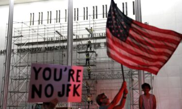 People wait for President Donald Trump's name to be removed from the John F. Kennedy Center for the Performing Arts in Washington