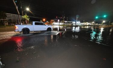 A motorist drives along a flooded road in Okaloosa County