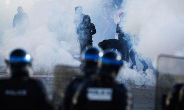 Police officers stand in front of protesters amid tear gas as demonstrators carry out blockading action near the Kerichen high school in Brest