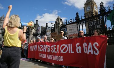 Protesters stand behind a banner saying 'No New North Sea Oil And Gas' with signs in London