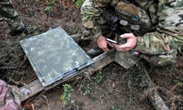 A soldier uses a smartphone to check signal quality while setting up a Starlink satellite communication network in the Donetsk region